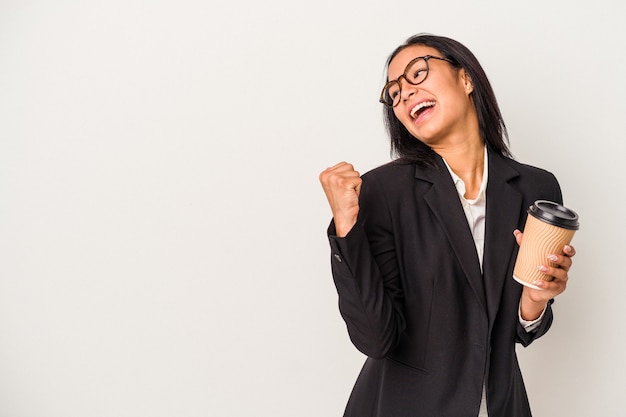 Young business latin woman holding a take away coffee isolated on white background  points with thumb finger away, laughing and carefree.