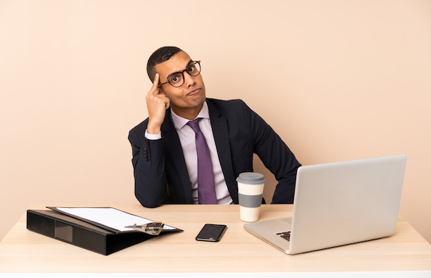 Young business man in his office with a laptop and other documents thinking an idea