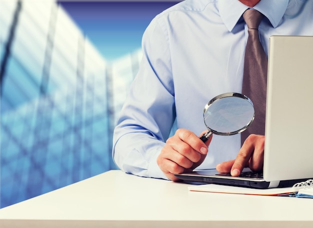 Young business man holding magnifying glass