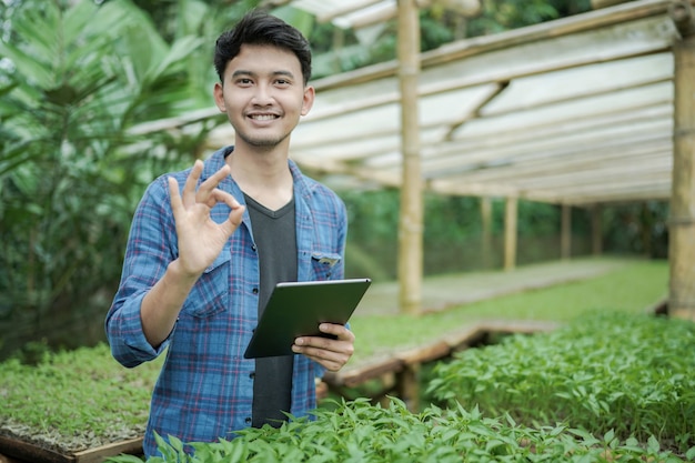 young business man holding a tablet and showing ok gesture while smiling to the camera