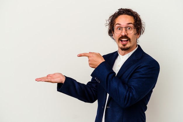 Young business man isolated on white excited holding a copy space on palm.