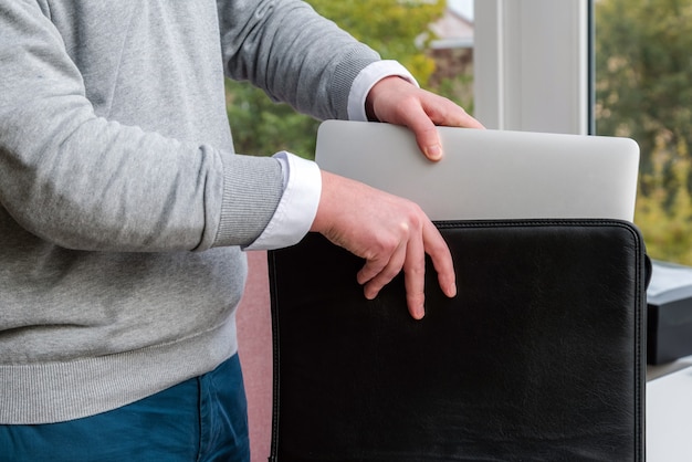 Young business man pulling out a laptop out of a leather case at the office.