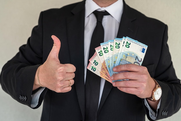 Young business man showing fan of euro banknotes