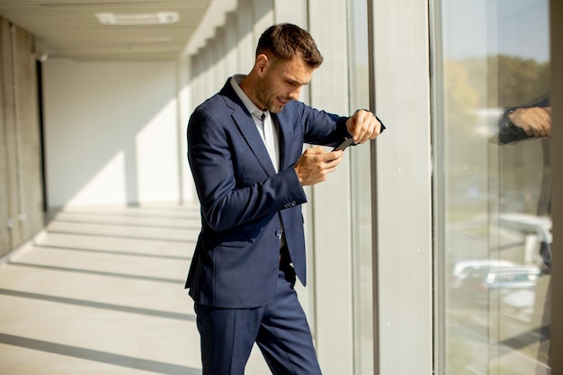 Young business man using mobile phone in the modern office hallway