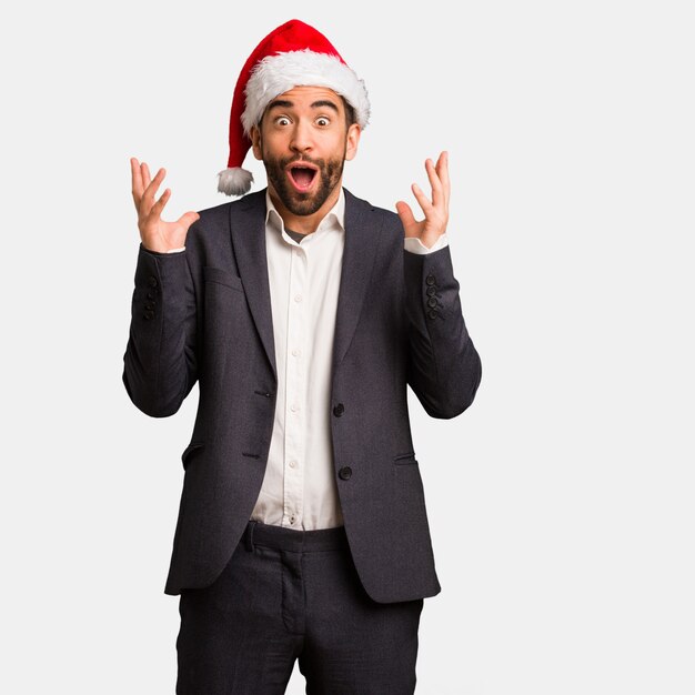 Young business man wearing santa hat celebrating a victory or success