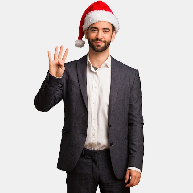 Young business man wearing santa hat showing number four