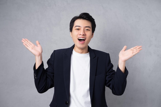 Young business man wearing a suit posing on a grey background