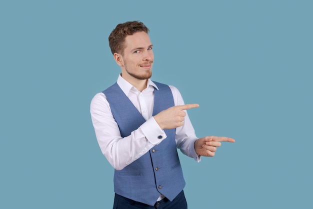 Young business man in white shirt and blue suit vest isolated on blue