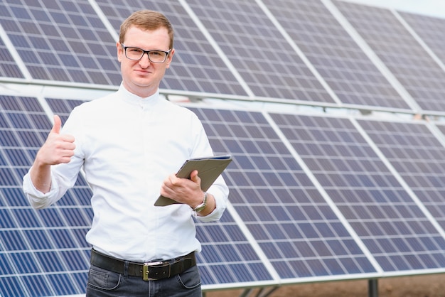 Young business man in a white shirt near the solar panels to power plants