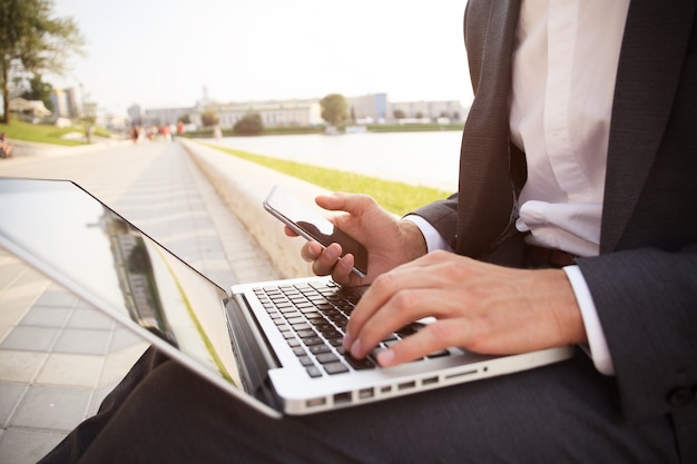 Young business man working on a laptop sitting on the street.