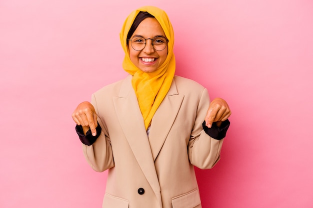 Young business muslim woman isolated on pink background points down with fingers, positive feeling.