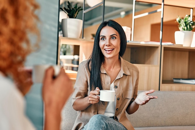 Young business partners drinking coffee in coffeeshop Female friends talking in cafe and spending time together