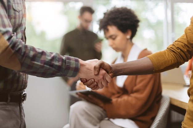 Young business partners shaking hands close up