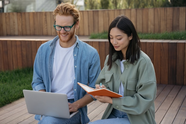 Young business people meeting using laptop working together outdoors