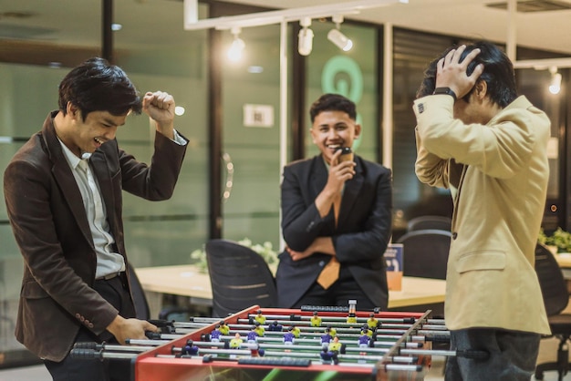 Young business people in suit playing table football during break time at the office