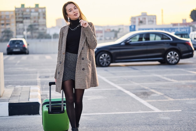 Young business woman against black luxury car