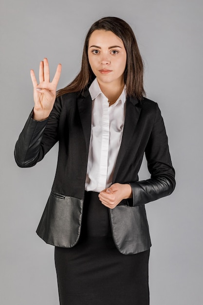 Young business woman in dark suite on grey background