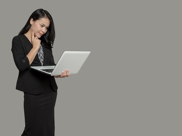 Young business woman holding laptop with finger on cheek