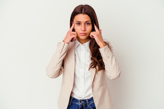 Young business woman isolated on white wall focused on a task, keeping forefingers pointing head