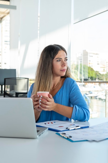 Young business woman on laptop at office with a thoughtful attitude