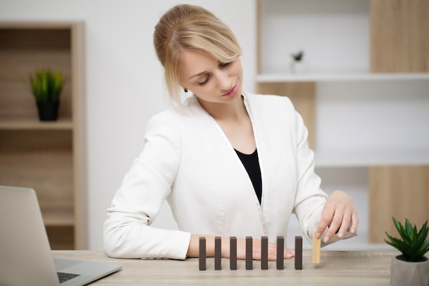 Young business woman in the office makes wooden cubes.