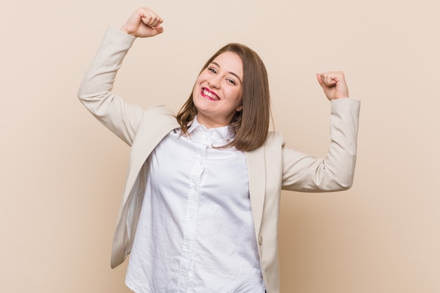 Young business woman showing strength gesture with arms, symbol of feminine power