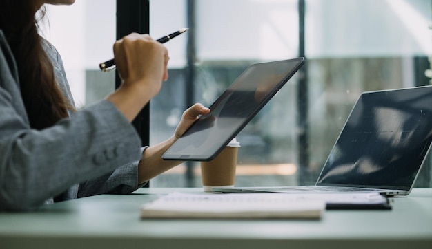 Young business woman sitting in office at table and using smartphone On desk is laptop and tablet computer on screen charts and graphs Woman analyzing data Student learning online