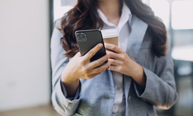 Young business woman sitting in office at table and using smartphone On desk is laptop and tablet computer on screen charts and graphs Woman analyzing data Student learning online