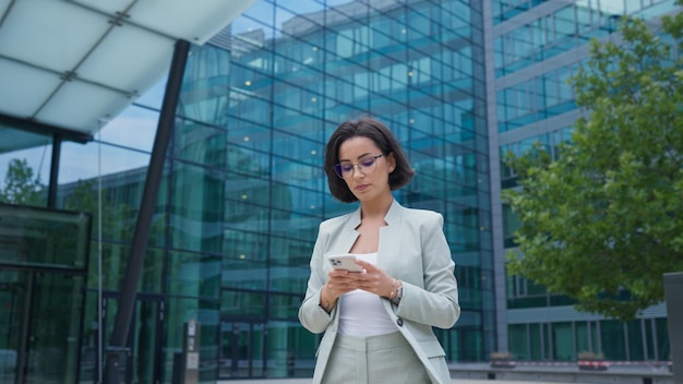 Young business woman smiling answering message using gadget device while looking at the camera