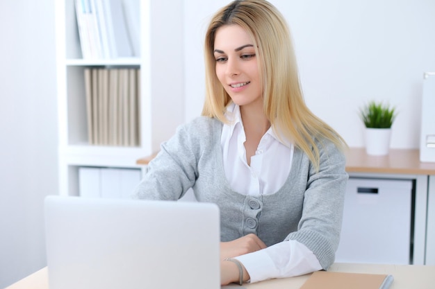 Young business woman or student girl sitting at office workplace with laptop computer. Home business concept.