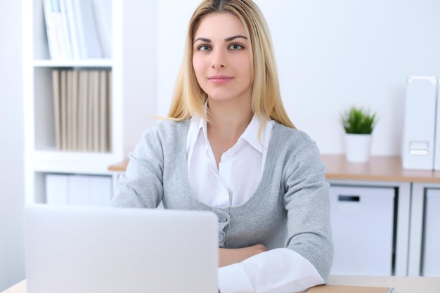 Young business woman or student girl sitting at office workplace with laptop computer. Home business concept.