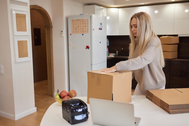 Young business woman taping up a cardboard box in the office relocation and new business concept