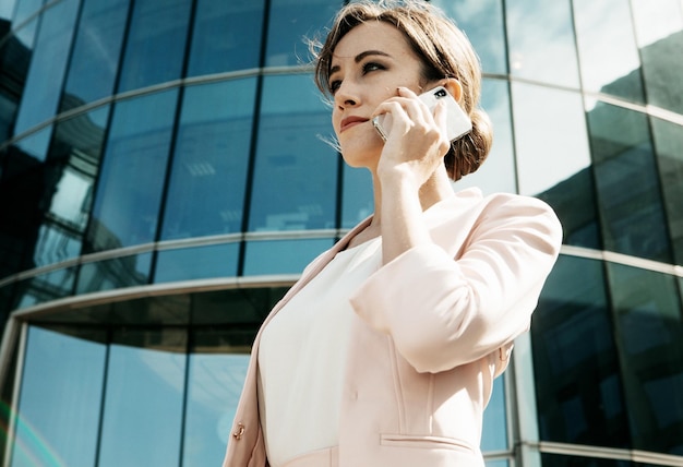 Young business woman uses a mobile phone in front of a modern business center