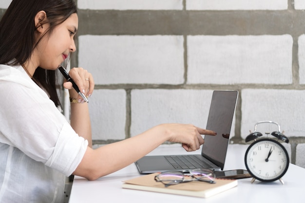 Young business woman using laptop and pointing on desktop screen.