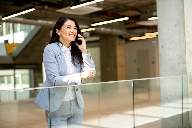 Young business woman using mobile phone in the office hallway