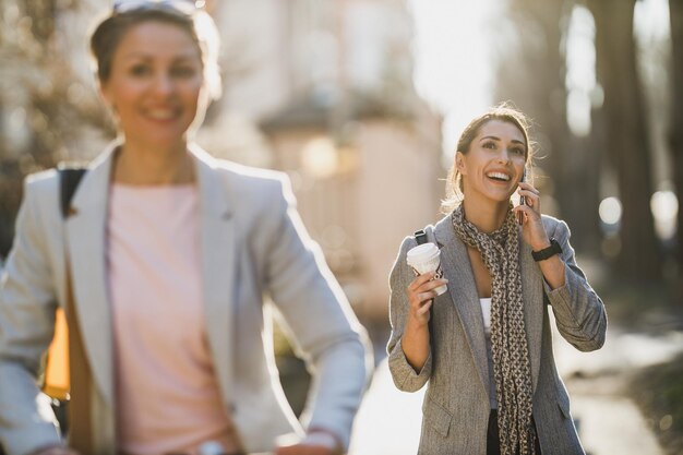 A young business woman using a smartphone while having a coffee break at city street.