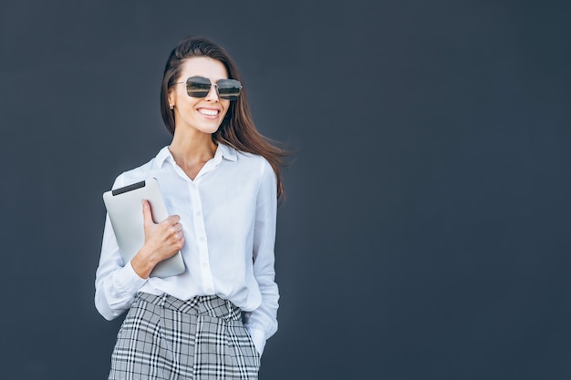 Young business woman with coffee and tablet on grey background.