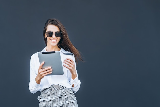 Young business woman with coffee and tablet on grey background