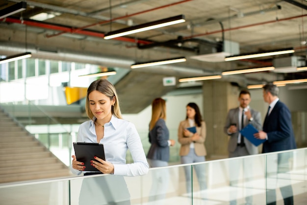 Young business woman with digital tablet in the office hallway