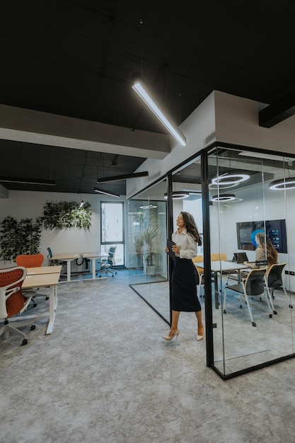 Young business woman with digital tablet walking in the modern office