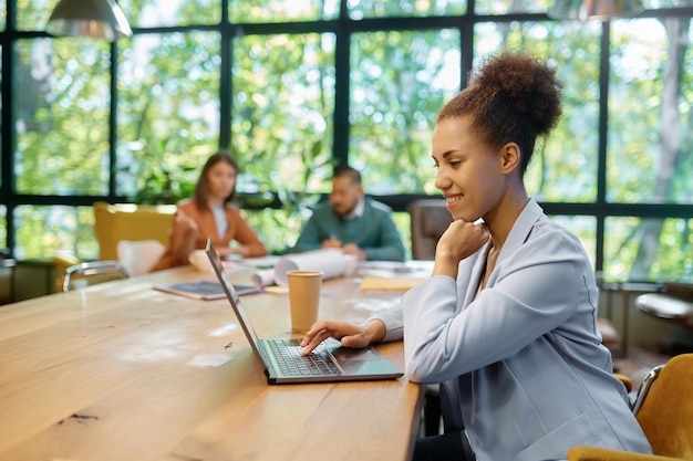 Young business woman working on laptop at shared open workspace