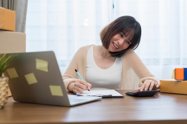 Young business woman working online ecommerce shopping at her shop Young woman seller prepare parcel box of product for deliver to customer