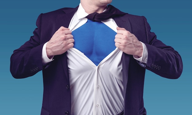 Young businessman acting like a super hero and tearing his shirt off with copy space