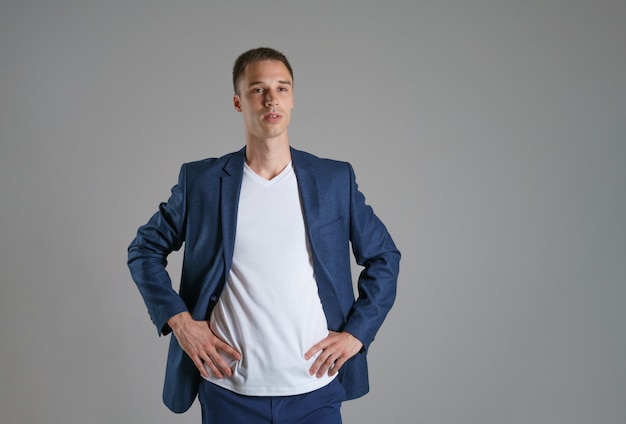 A young businessman in a blue jacket on a gray wall