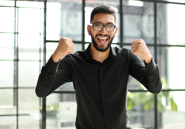 Young businessman celebrating success in his home office