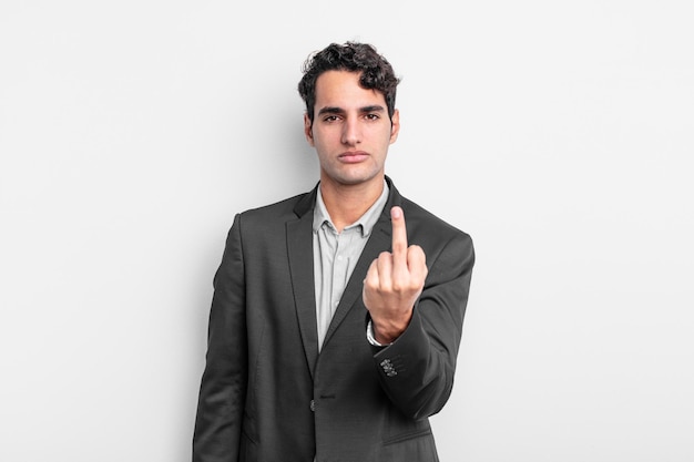 Young businessman feeling angry, annoyed, rebellious and aggressive, flipping the middle finger, fighting back