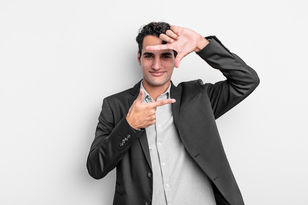 Young businessman feeling happy, friendly and positive, smiling and making a portrait or photo frame with hands