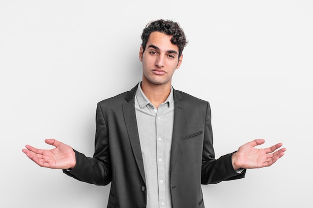 Young businessman feeling puzzled and confused, unsure about the correct answer or decision, trying to make a choice