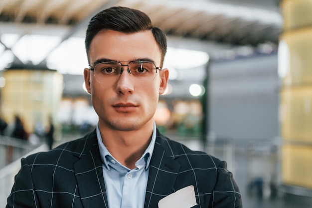 Young businessman in formal clothes is in the airport at daytime