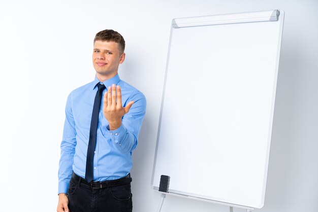 Photo young businessman giving a presentation on white board inviting to come with hand. happy that you came